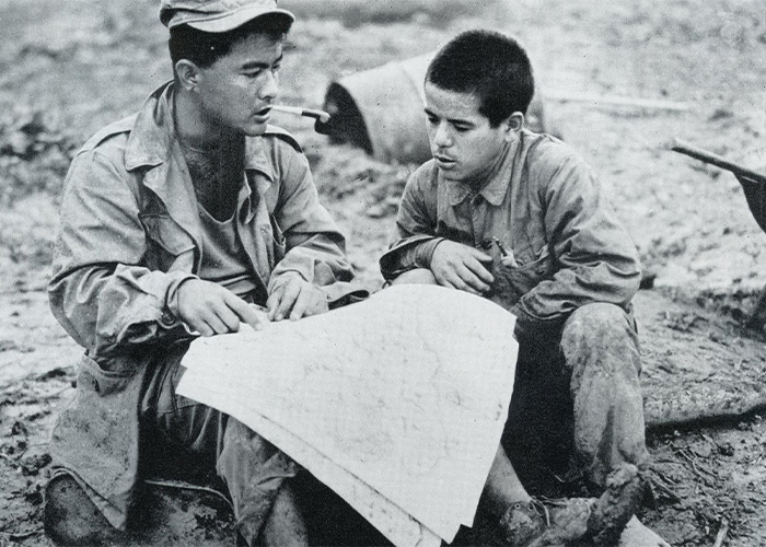 OKINAWA, 1945: Warren Higa, left, of Honolulu, questions a prisoner about Japanese positions; Higa and his brother Takejiro were from Hawaii but went to school on Okinawa. (Photo: U.S. Army Signal Corps)