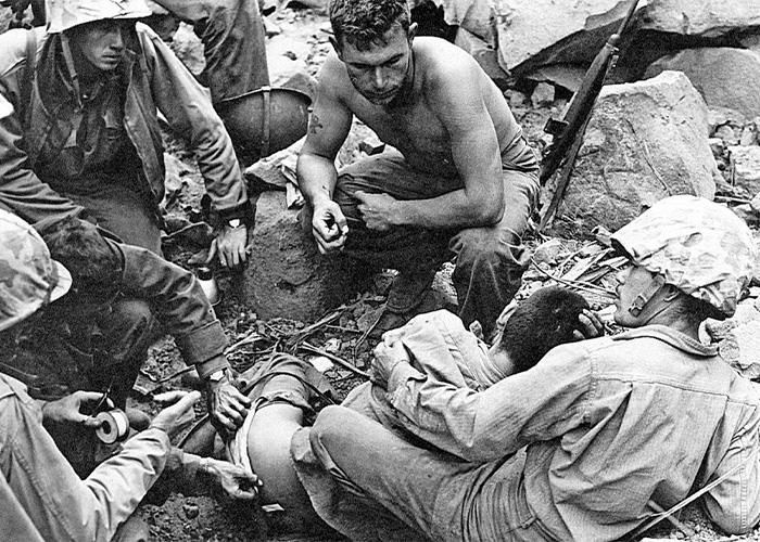 WO JIMA, March 9, 1945: Tom Miyagi, MIS linguist with the 5th Marine Division, holds a captured Japanese soldier while marines treat the prisoner’s wounds. (Photo: U.S. Marine Corps)